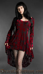 Woman wearing a black and red gothic burnout velvet high-low dress with rose pattern, long flared bell sleeves, square neckline and flowing asymmetrical hem