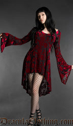 Woman wearing a black and red gothic burnout velvet high-low dress with rose pattern, long flared bell sleeves, square neckline and flowing asymmetrical hem