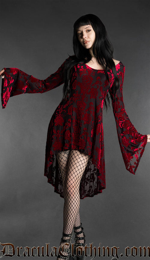 Woman wearing a black and red gothic burnout velvet high-low dress with rose pattern, long flared bell sleeves, square neckline and flowing asymmetrical hem