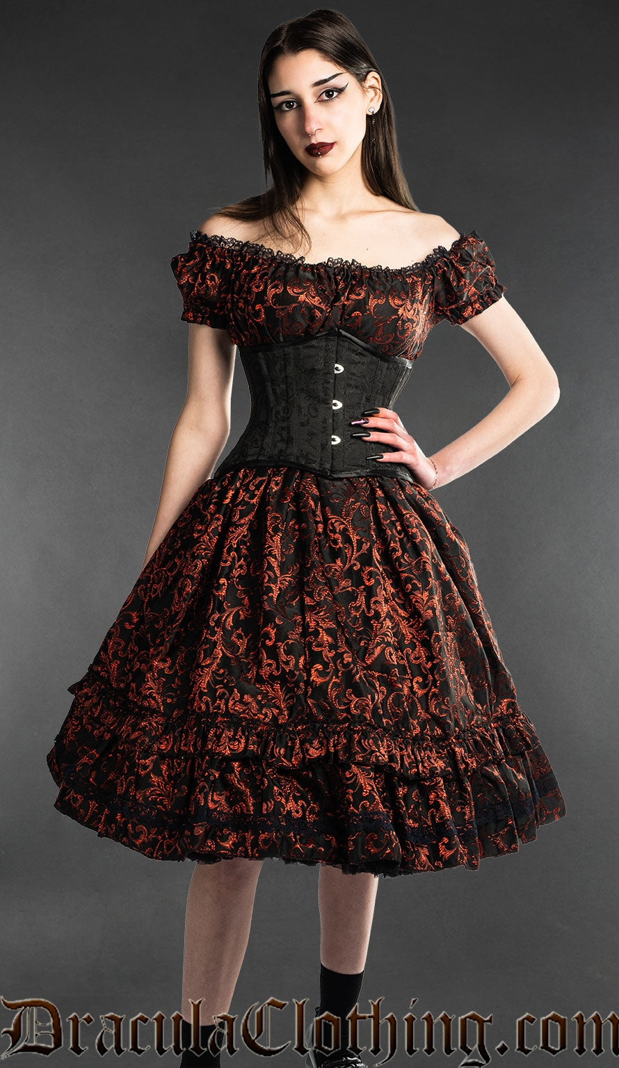 Model wearing black and red brocade knee length dress with black waist cincher