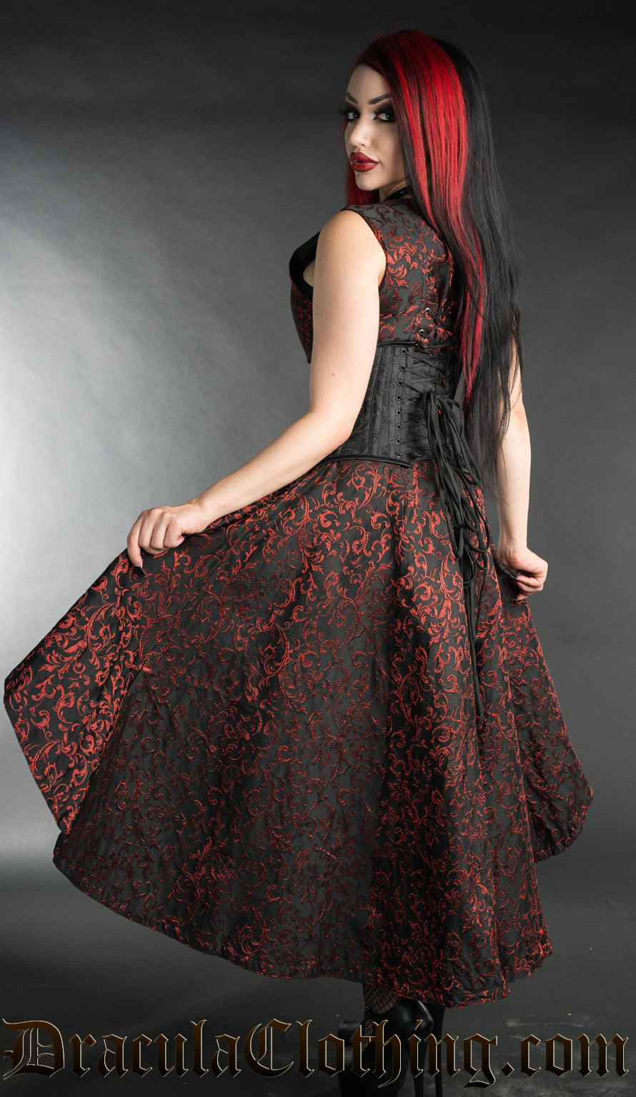Back view of model wearing women's black and red dress with additional waist cincher showing long skirt in the back