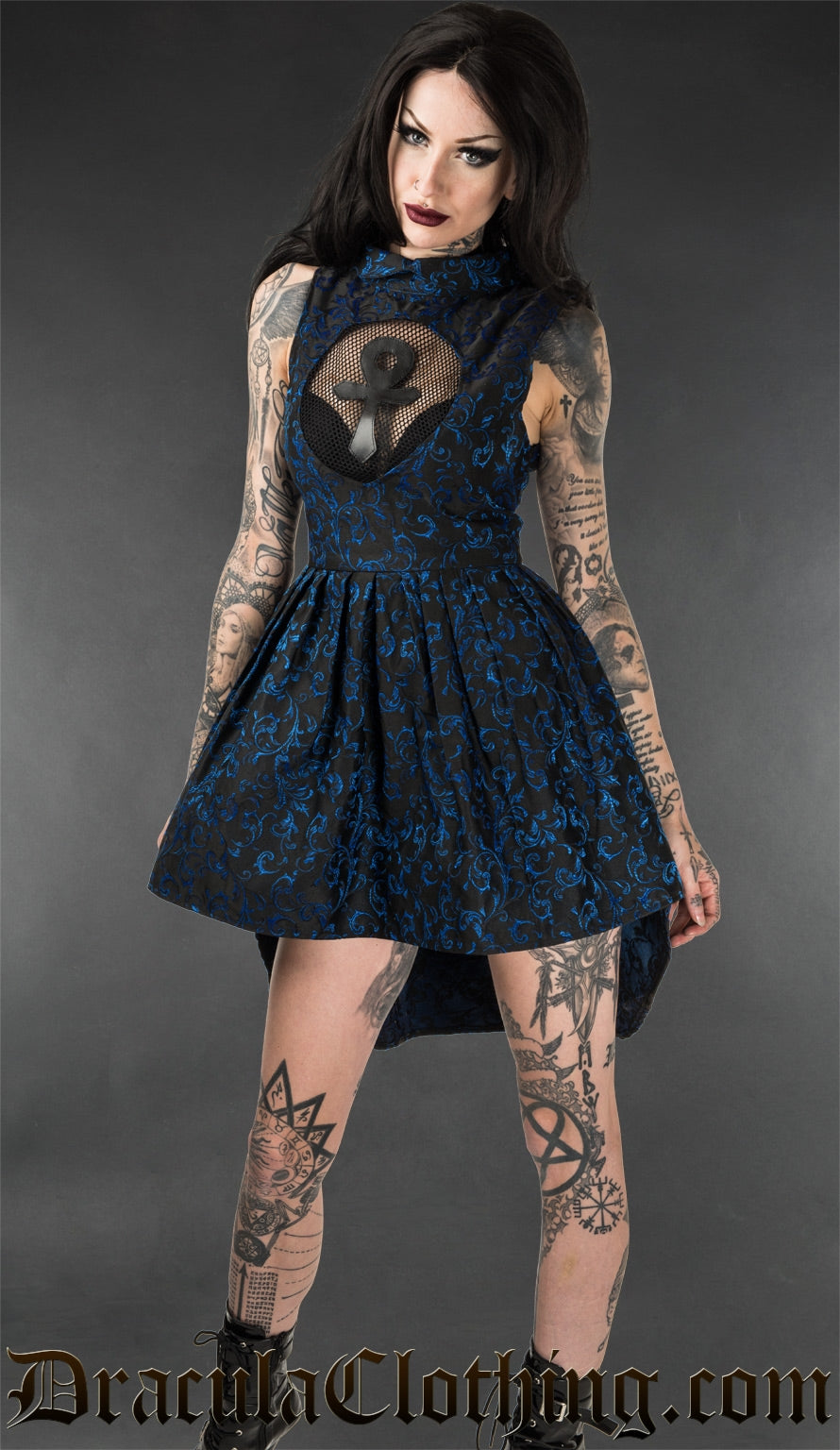 Model wearing blue brocade short high low dress with mesh illusion keyhole panel and ankh motif