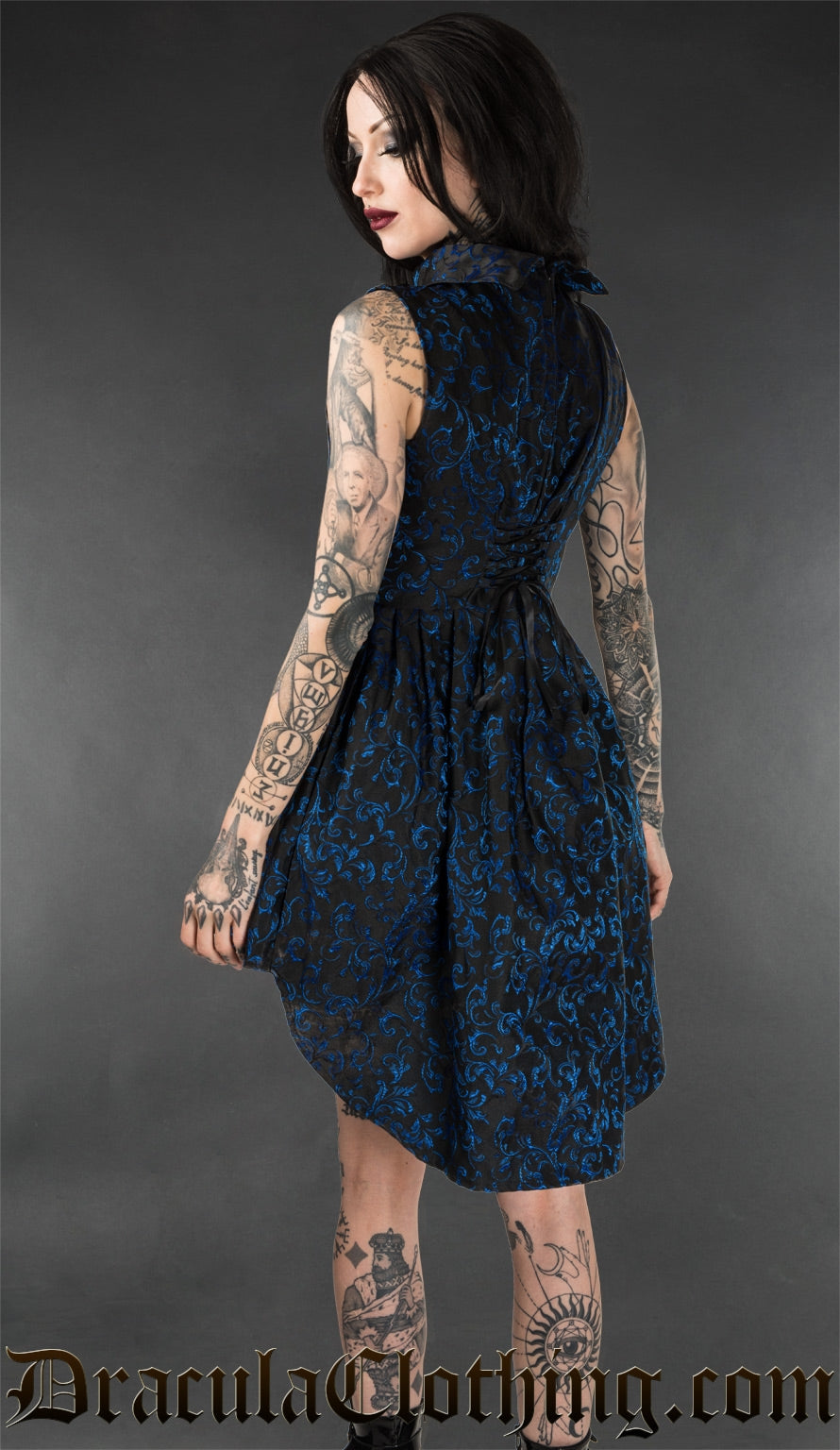 Back view of model wearing blue sapphire brocade sleeveless high low dress showing adjustable corset style lacing in the back