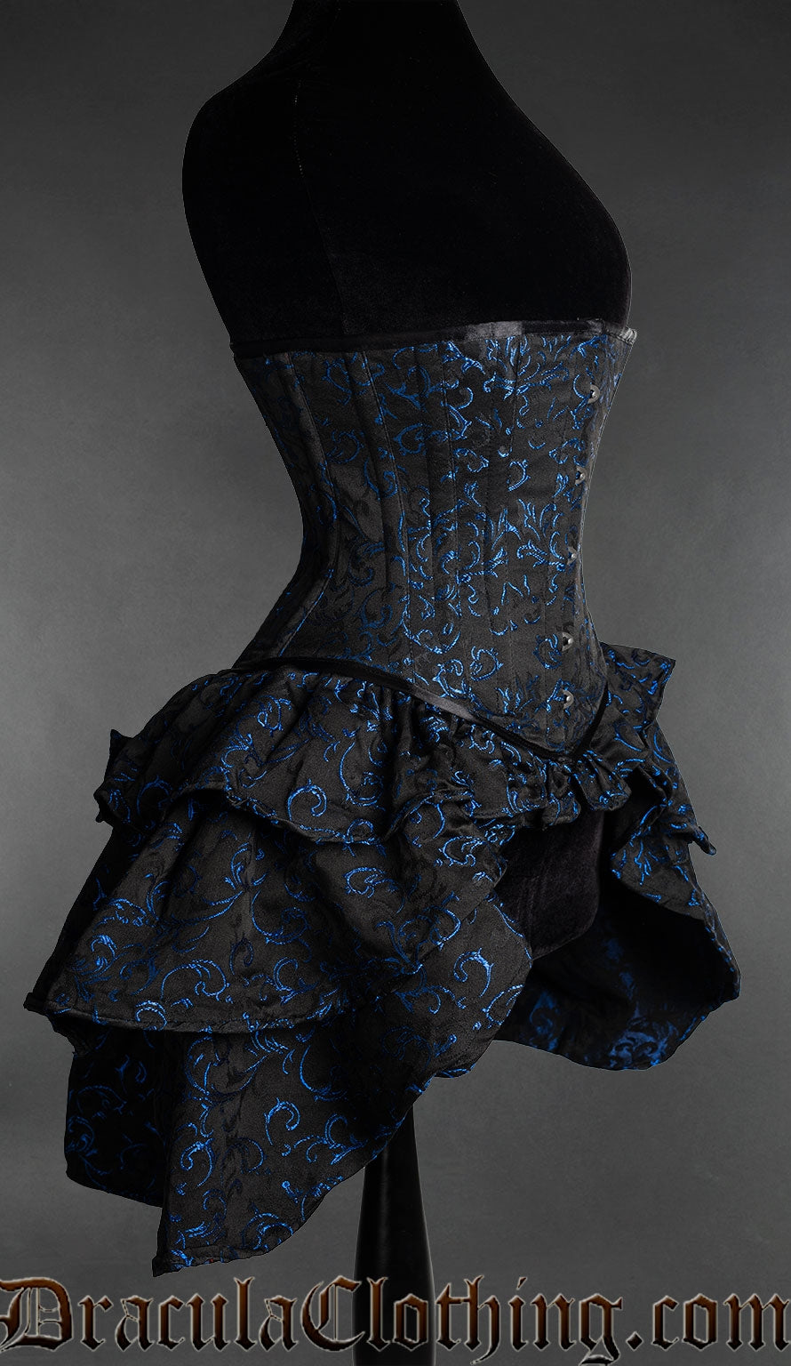 Side view of black and blue woven brocade corset showing layered ruffled bustle fabric