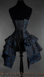Back view of black and blue woven brocade corset with bustle skirt attachment showing adjustable lacing and matching fabric modesty panel