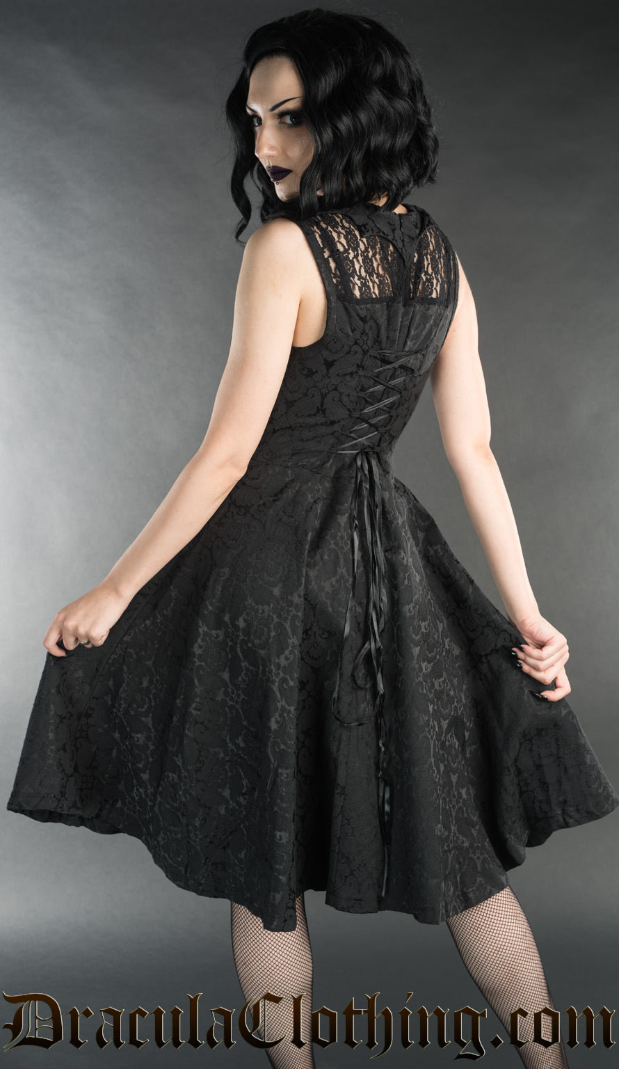 Model showing back of knee length bat black brocade dress with adjustable corset style lacing in the back