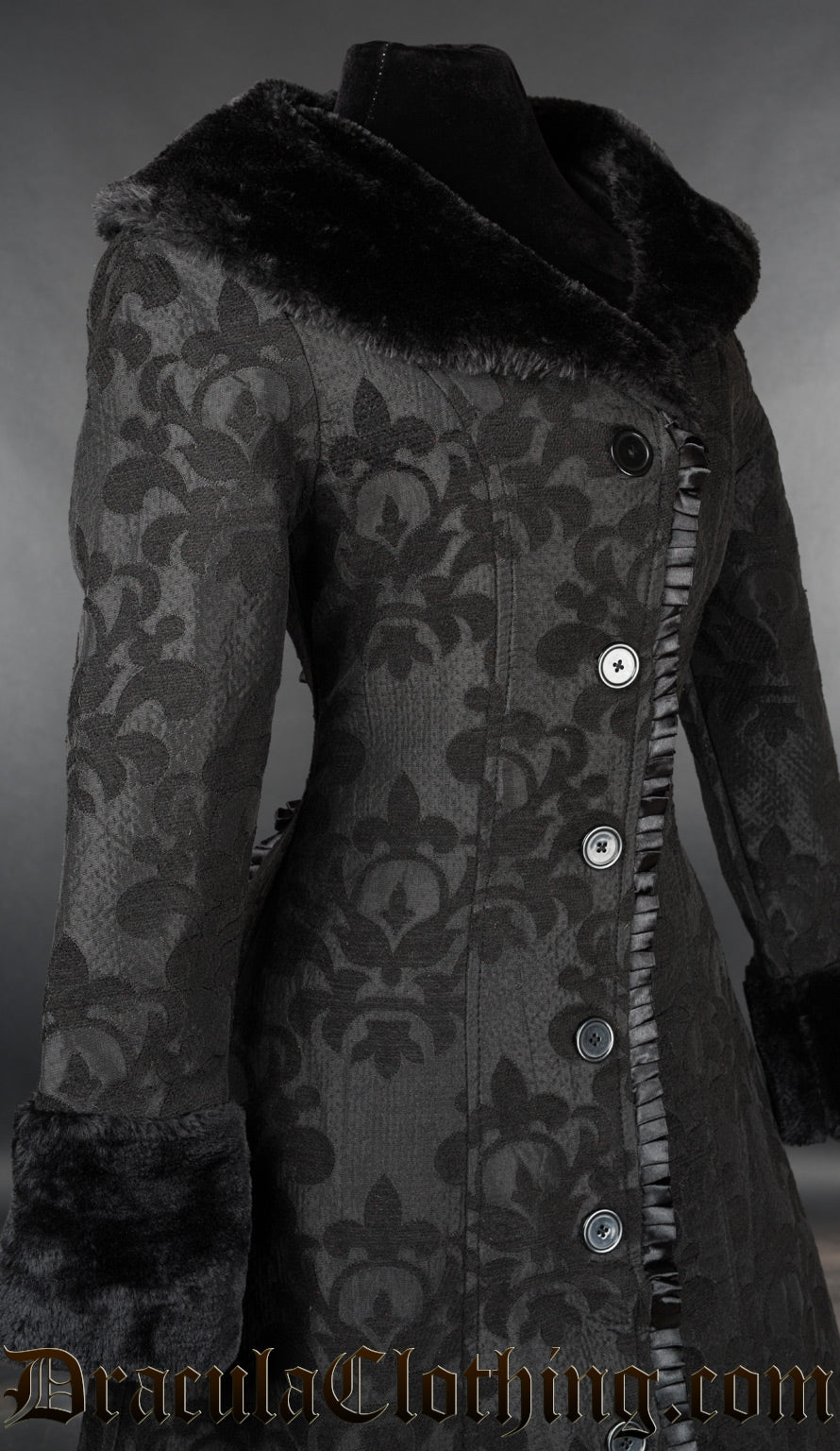 Close up side view of women's black coat showing black skull brocade design in the fabric and a ruffled satin trim hem