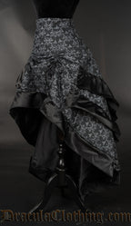 Side view of black and grey layered bustle skirt with hidden skull, showing layered fabric at the back and skirt raised in the front