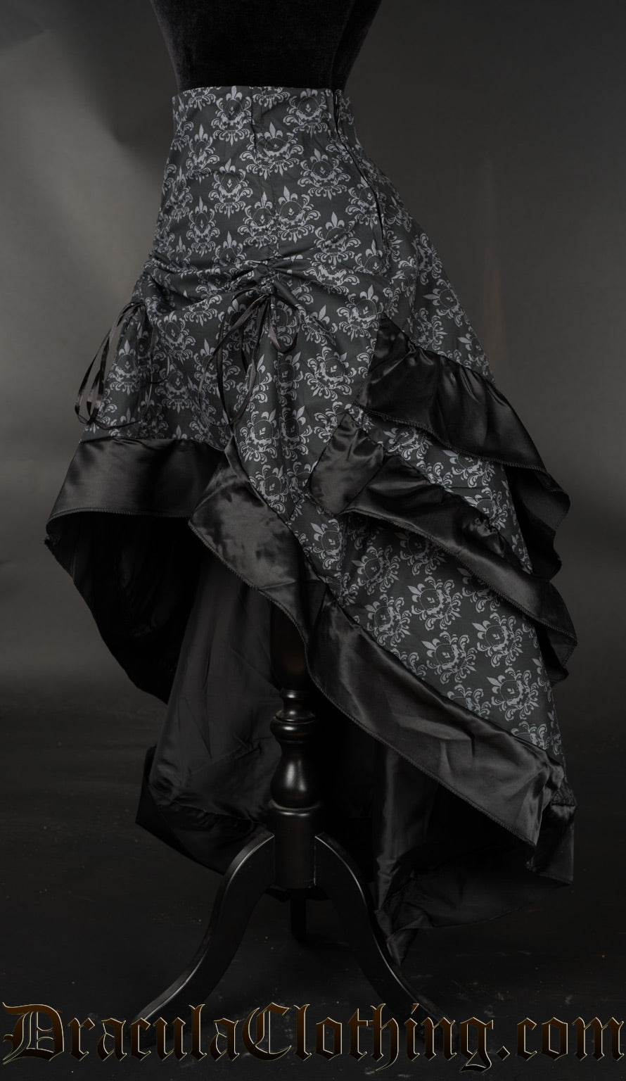 Side view of black and grey layered bustle skirt with hidden skull, showing layered fabric at the back and skirt raised in the front