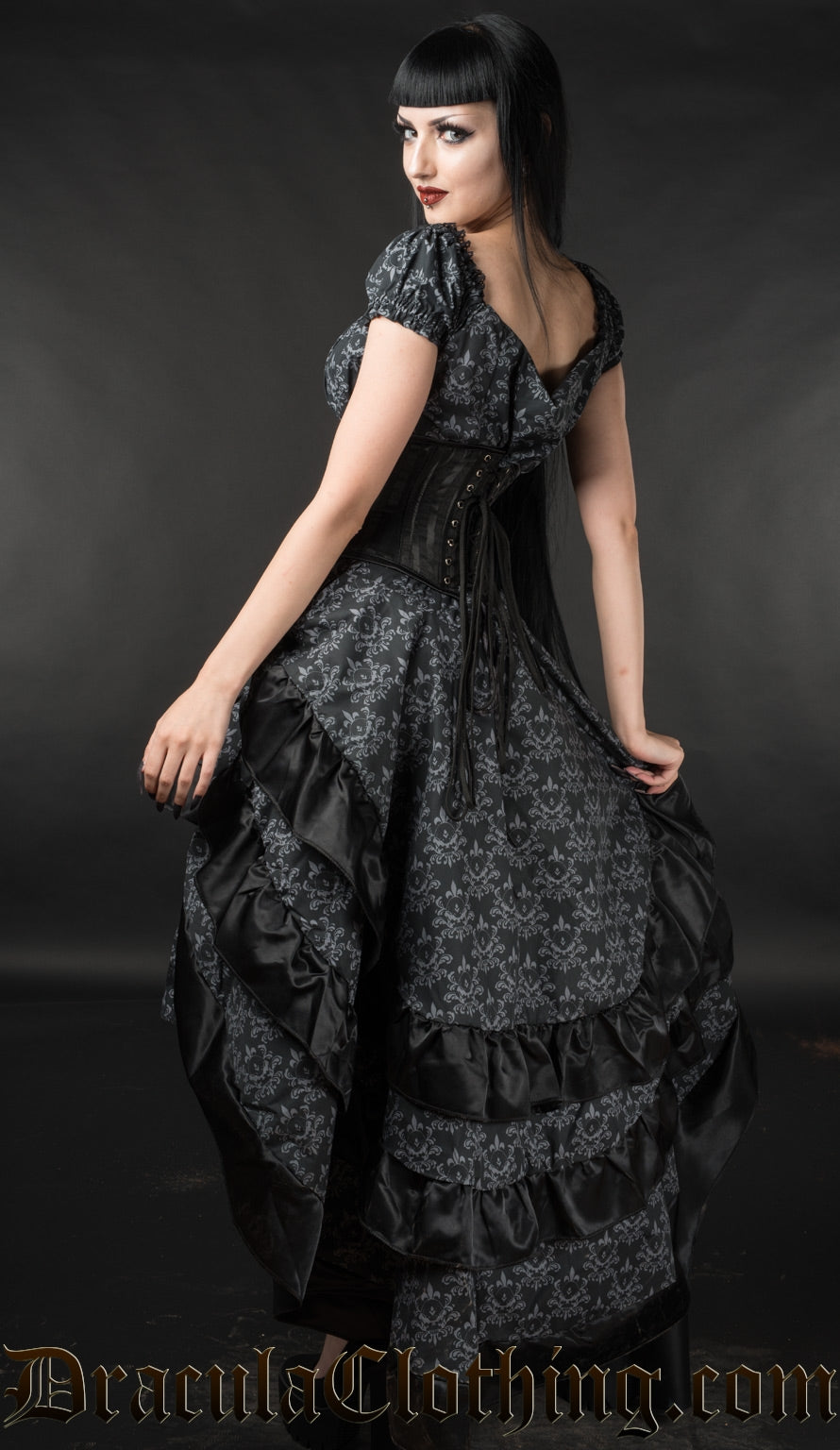 Model showing back of skull brocade bustle skirt wearing matching dress and black waist cincher