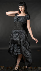 Model wearing skull print black knee length dress with additional waist cincher and matching fabric bustle skirt