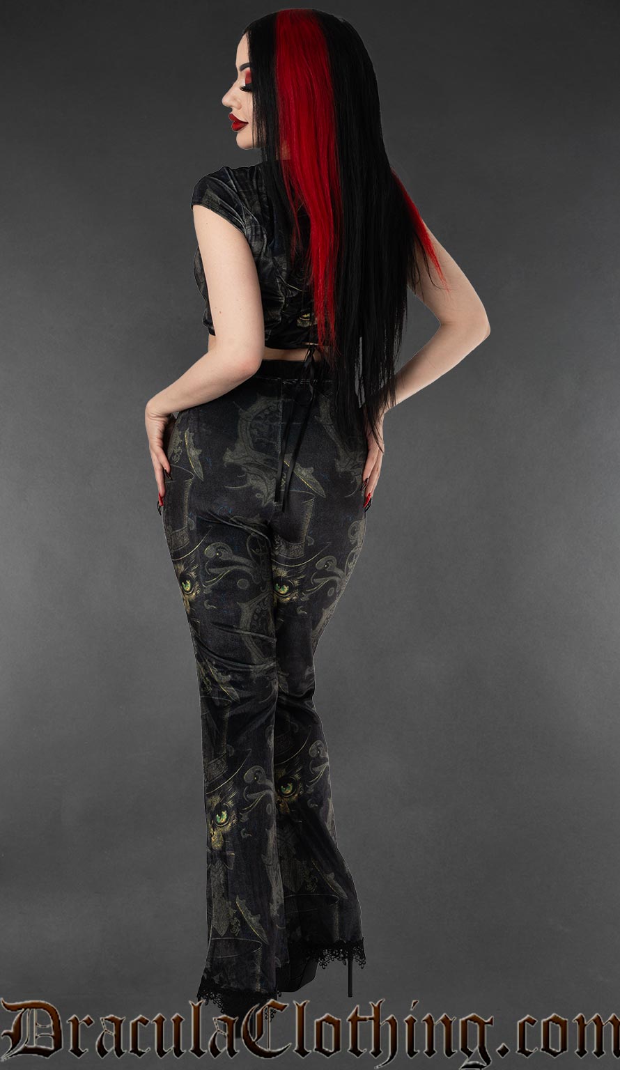 Back view of women's velvet flared pants featuring a printed ornate sphinx cat design on a black background