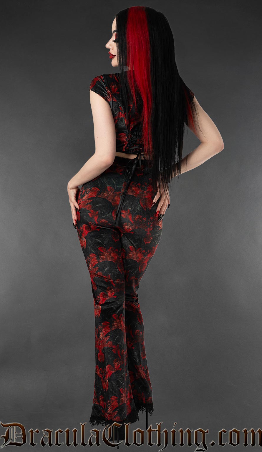 Model wearing black and red velvet flare pants with vampire bat print back view