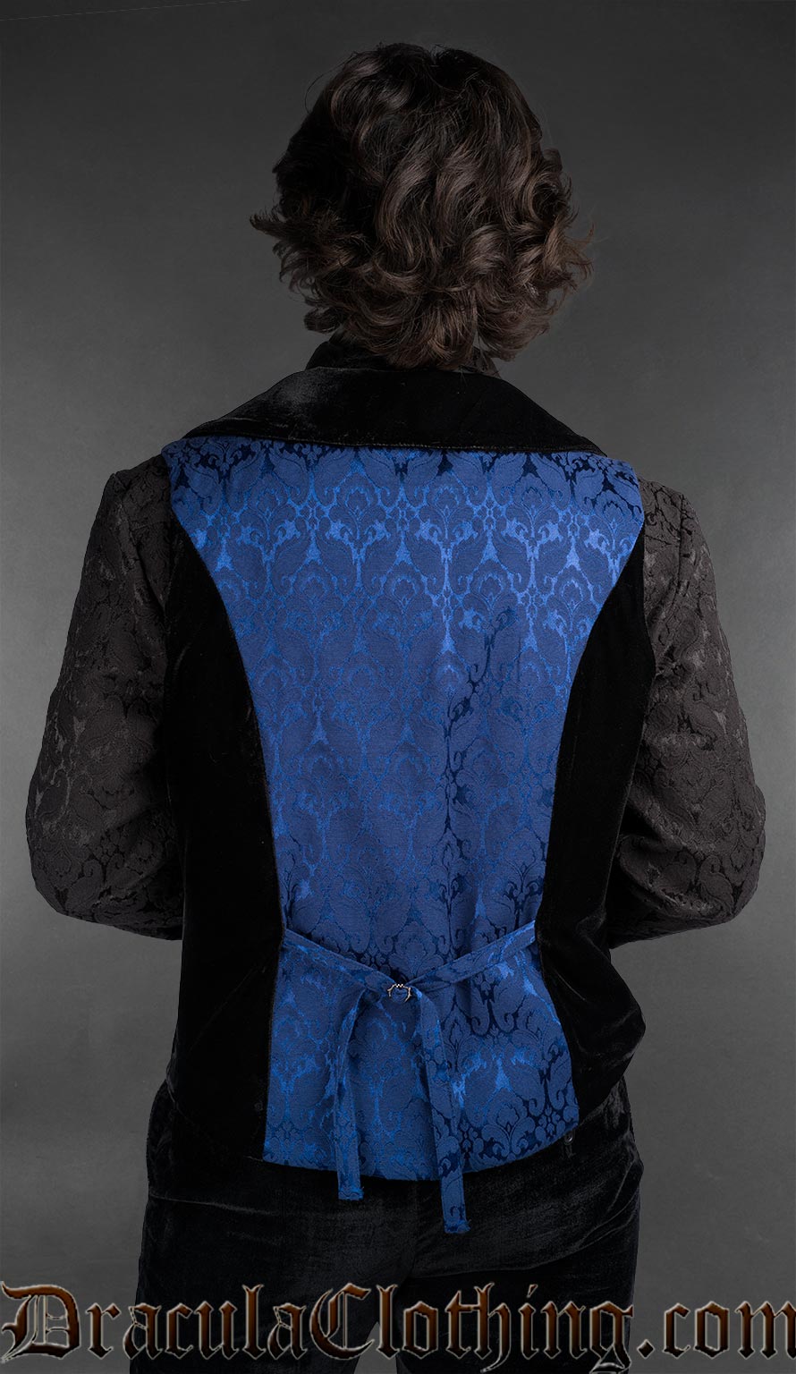 Back view of Men’s blue brocade gothic vest with black velvet details, worn over a black patterned shirt, Victorian alternative fashion