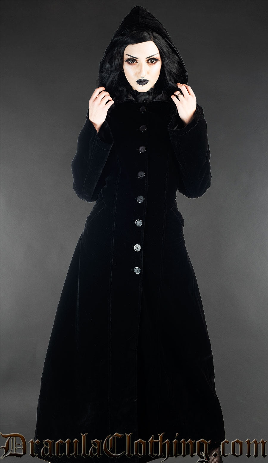 Model wearing black velvet women's coat with the attached hood up