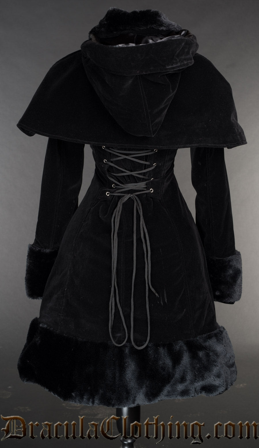 Back view of women's black velvet winter coat showing detachable cape and adjustable corset style lacing in the torso
