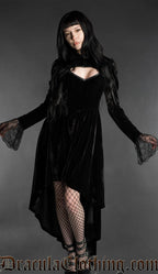Woman wearing a black gothic velvet vampire dress with sweetheart neckline, lace bell sleeves and high-low hem
