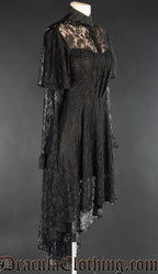 Side view of women's black lace dress showing layered long sleeves made from sheer lace and high low style skirt that is longer in the back