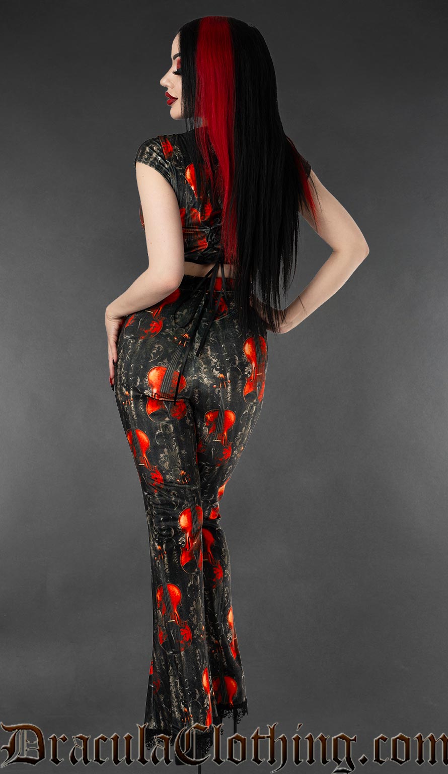 Back view of high waisted flared velvet pants in black and grey with a violin print